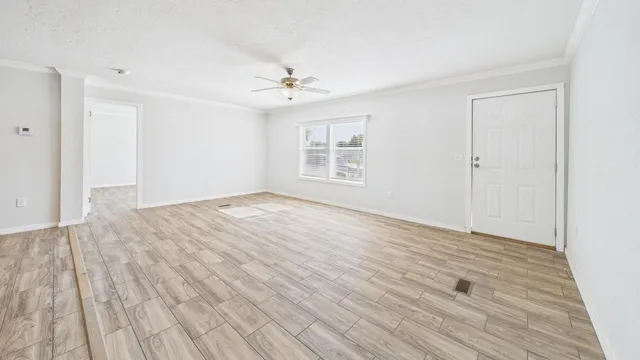 a view of empty room with wooden floor and fan