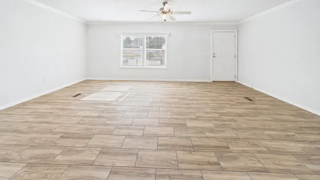 an empty room with wooden floor and windows