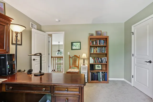 a room with a bookshelf a desk and painting on the wall