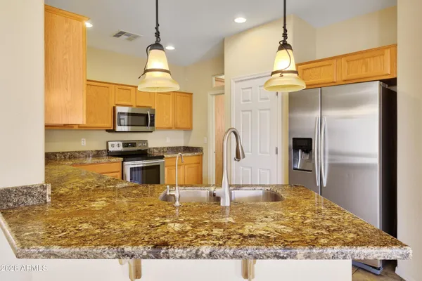 a kitchen with kitchen island granite countertop a stove a refrigerator and a sink