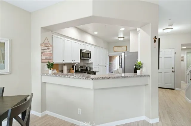 a view of a kitchen with kitchen island a sink stainless steel appliances wooden floor and cabinets