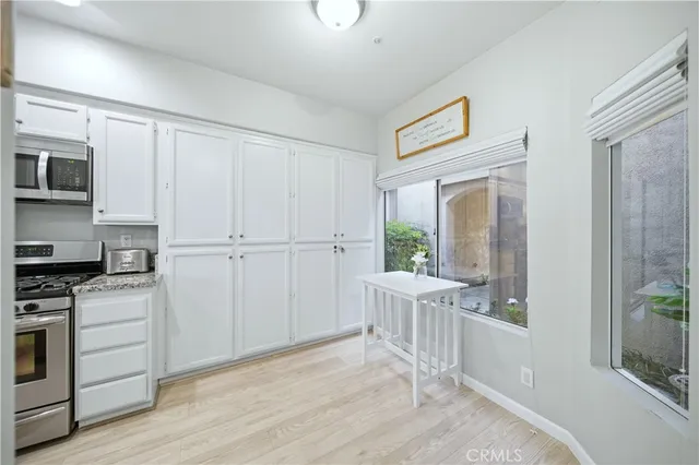 a view of a kitchen with white cabinets and wooden floor