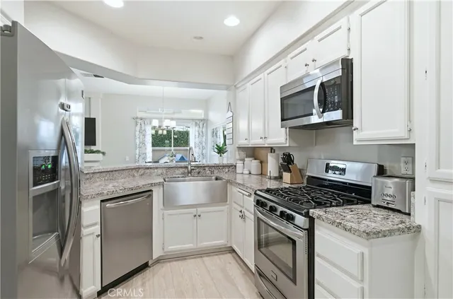 a kitchen with stainless steel appliances granite countertop white cabinets a sink a stove a microwave and island