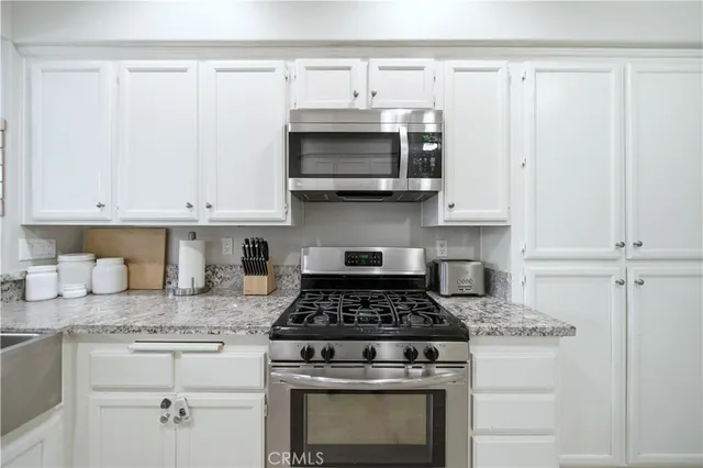 a kitchen with granite countertop white cabinets and stainless steel appliances