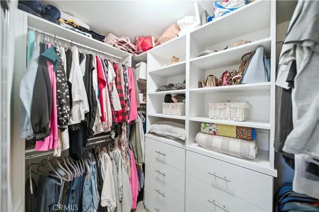 a view of walk in closet with clothes and shoes