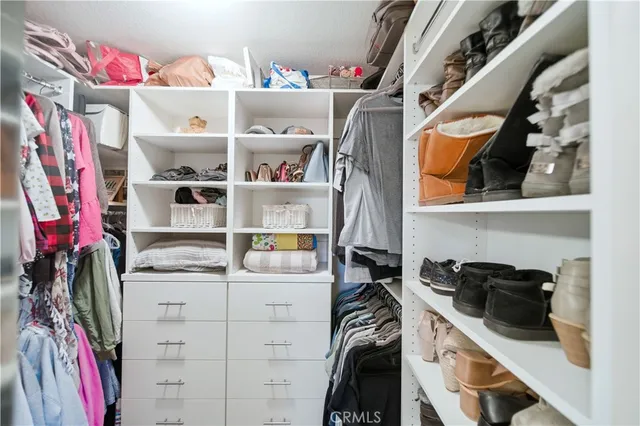 a view of walk in closet with clothes and shoes