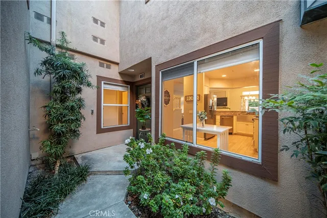 a view of yellow house with potted plants next to a road