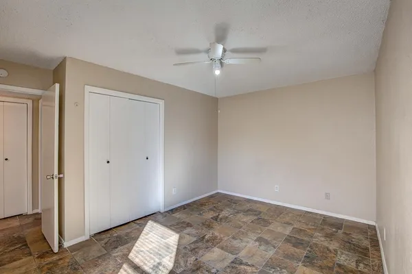 a view of an empty room with window and chandelier fan