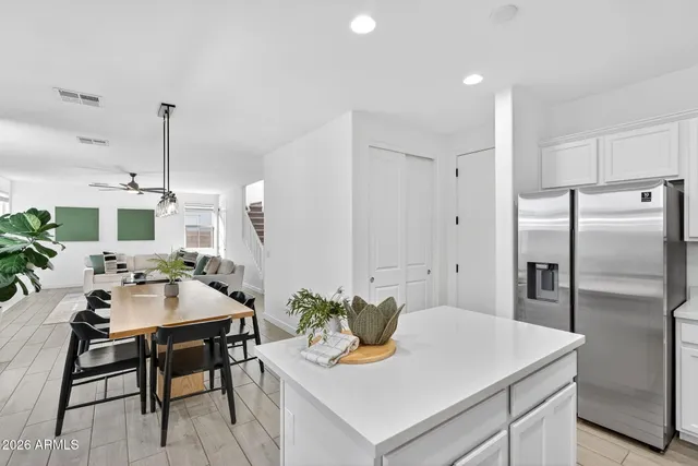 a kitchen with stainless steel appliances kitchen island granite countertop a refrigerator sink and white cabinets