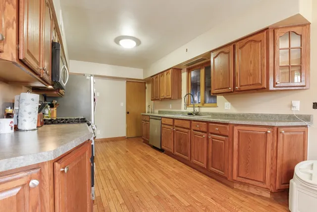 a kitchen with stainless steel appliances granite countertop a sink a stove cabinets counter space and a window