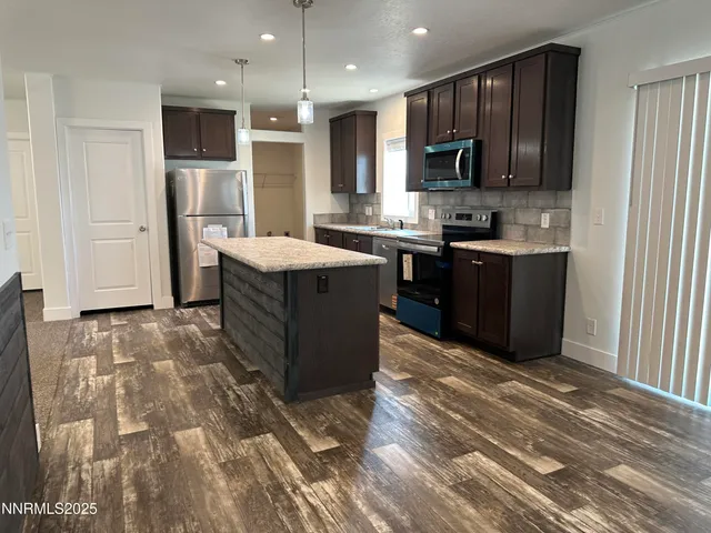 a kitchen with stainless steel appliances granite countertop a stove top oven a sink and a refrigerator