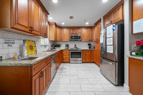 a kitchen with stainless steel appliances granite countertop wooden cabinets a sink and dishwasher with wooden floor
