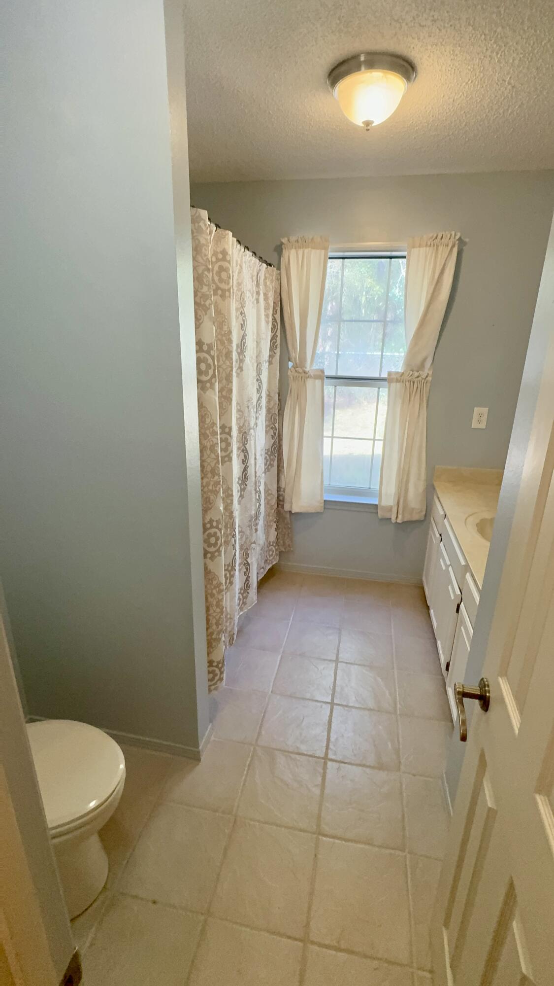 5957 Ridgecrest Road Crestview, FL 32539 - Photo 30 of 56 a bathroom with a granite countertop bathtub a window and a shower