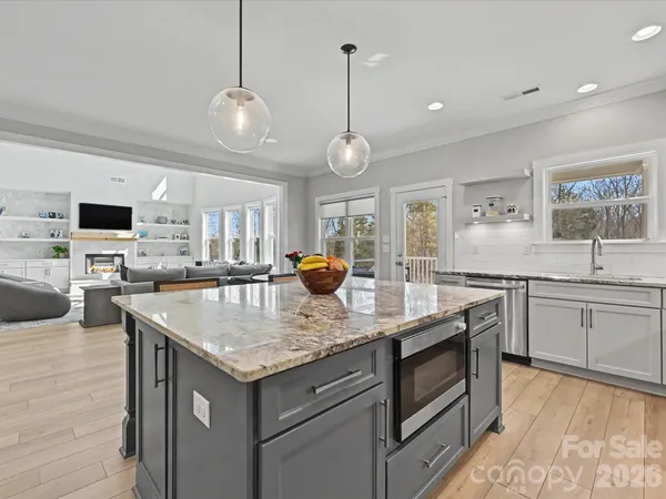 a kitchen with stainless steel appliances kitchen island granite countertop a table chairs stove and refrigerator