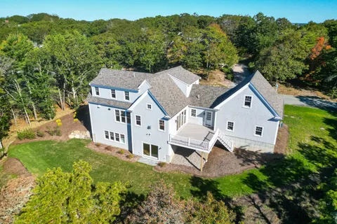 an aerial view of residential house with yard and trees around