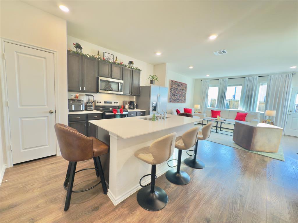 6000 Holly Spg Road Princeton, TX 75407 - Photo 11 of 27 a living room with kitchen couches kitchen view and a dining table with wooden floor