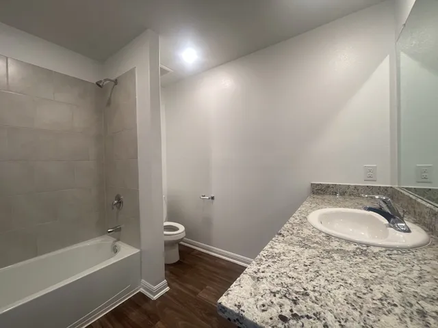 a bathroom with a granite countertop sink a toilet and bathtub