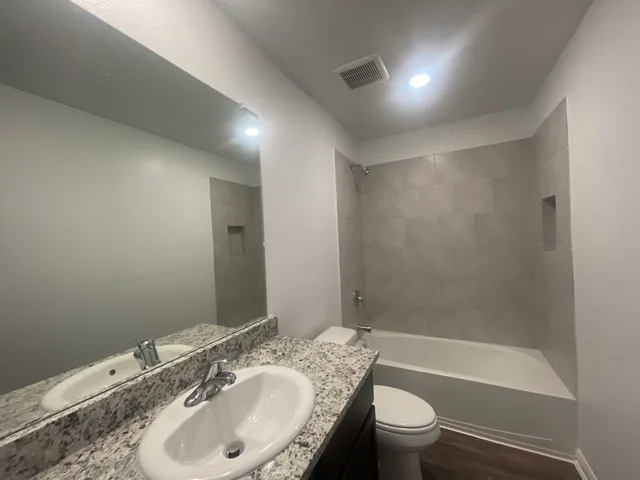a bathroom with a granite countertop sink a toilet and shower