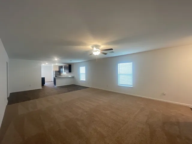 a view of empty room with windows and ceiling fan