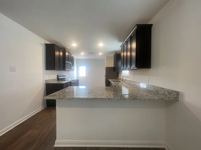 a large kitchen with a large counter top stainless steel appliances and cabinets