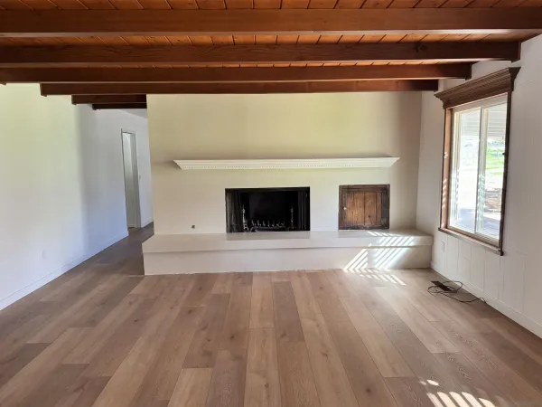 a view of empty room with wooden floor and fireplace