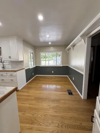 a view of kitchen and empty room with wooden floor