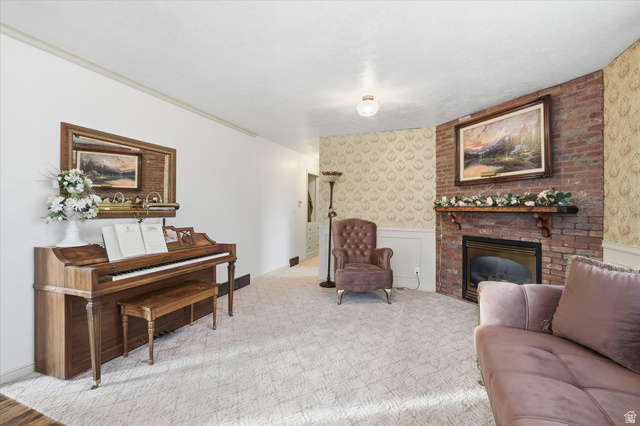165 Main Street Georgetown, ID 83239 - Photo 4 of 50 Carpeted living room with wallpapered walls, a brick fireplace, and a wainscoted wall