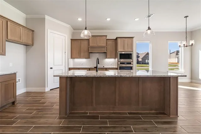 a kitchen with kitchen island granite countertop a sink cabinets and stainless steel appliances