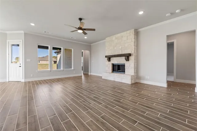 a view of an empty room with wooden floor fireplace and a window