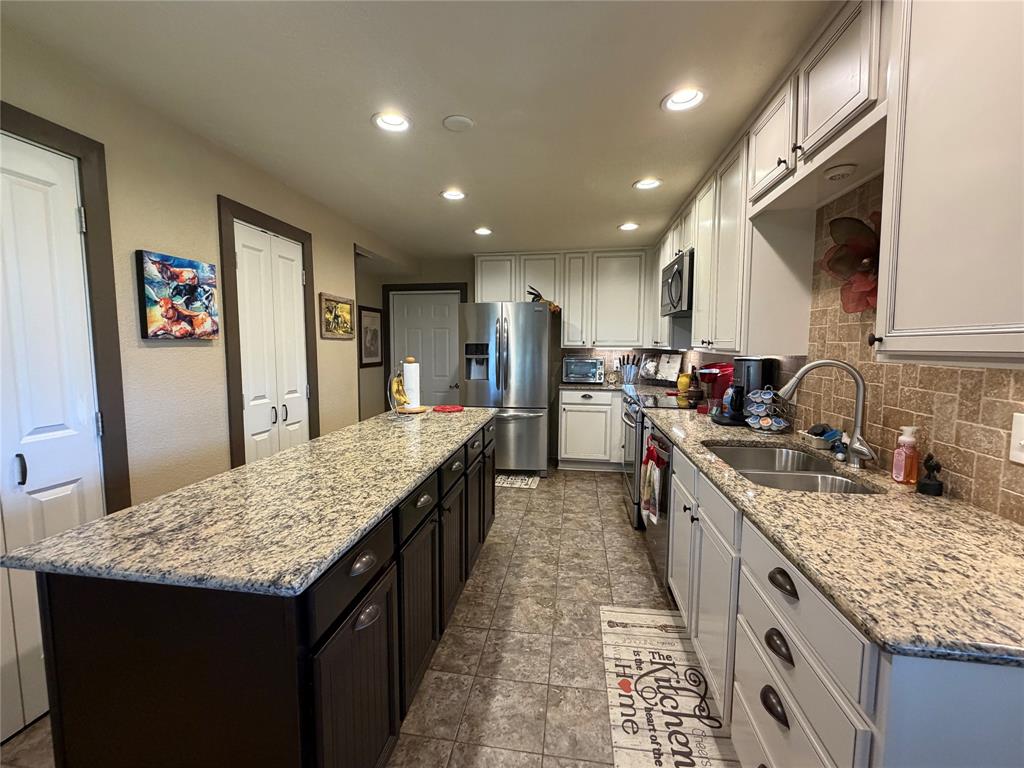 330 South Goode Road Wilmer, TX 75172 - Photo 17 of 38 a kitchen with granite countertop kitchen island stainless steel appliances a sink stove and cabinets