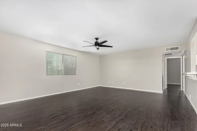 an empty room with wooden floor a ceiling fan and windows