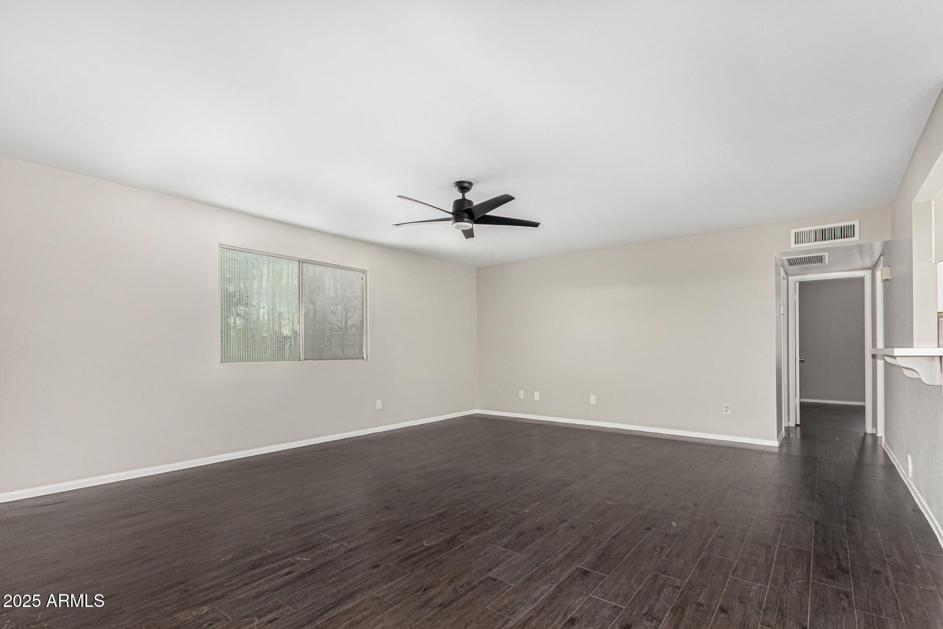 2133 West Turney Avenue, Unit D76 Phoenix, AZ 85015 - Photo 5 of 28 an empty room with wooden floor a ceiling fan and windows
