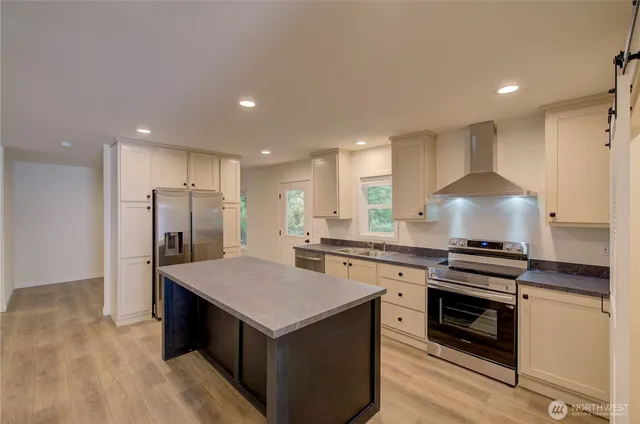 a kitchen with stainless steel appliances a kitchen island a stove and a refrigerator