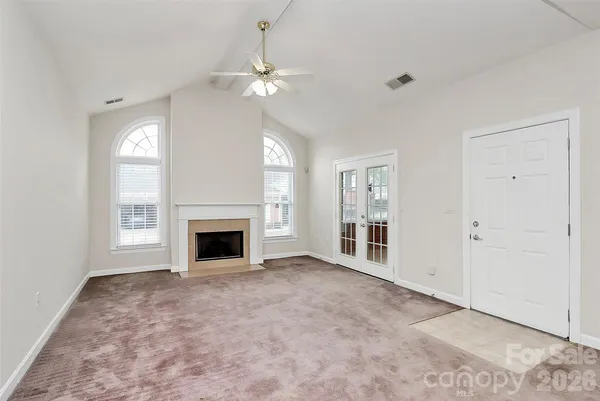 an empty room with windows and fireplace