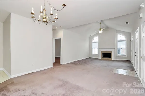 a view of a livingroom with a fireplace a chandelier and windows