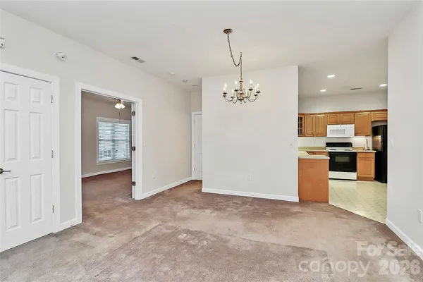 an empty room with kitchen view and wooden floor