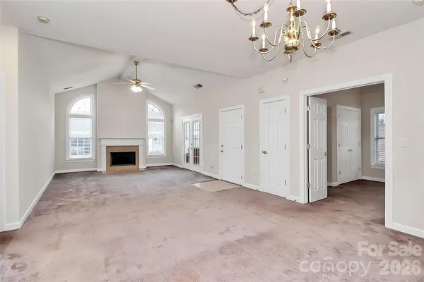 an empty room with a fireplace and chandelier