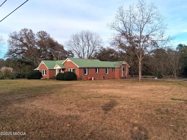 a front view of house with yard and trees in the background