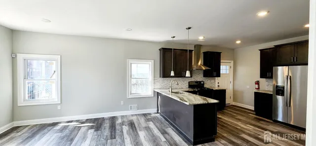 a kitchen with granite countertop kitchen island stainless steel appliances a sink stove and refrigerator
