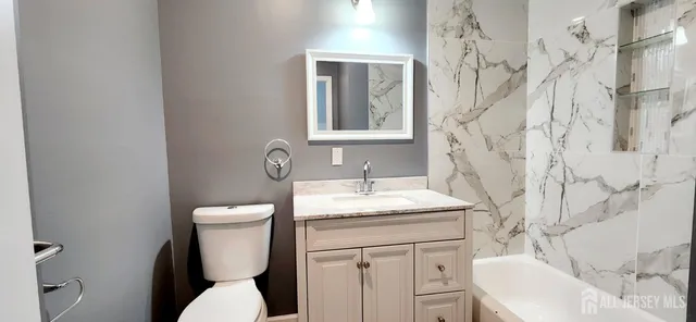 a bathroom with a granite countertop toilet sink and mirror