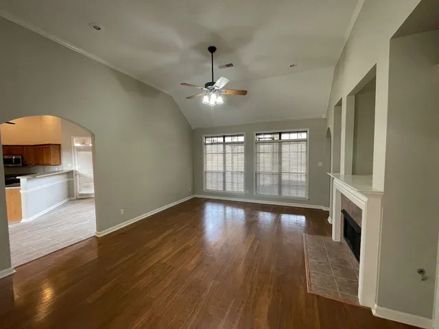 a view of empty room with wooden floor and fan
