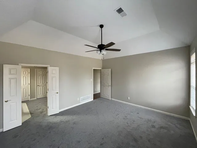 a view of an empty room with a chandelier fan