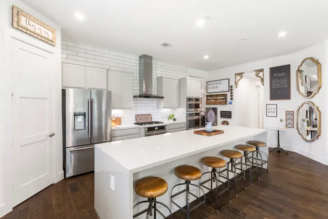 a kitchen with stainless steel appliances a refrigerator a stove a sink dishwasher with a dining table and chairs with wooden floor