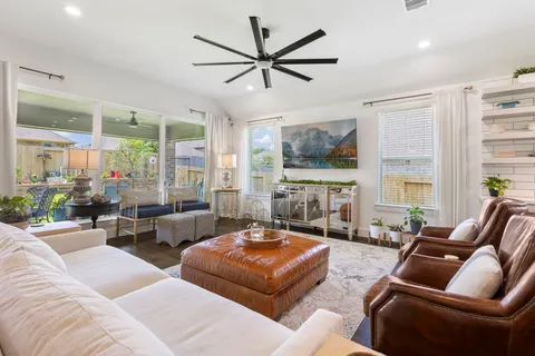 a living room with furniture ceiling fan and a large window