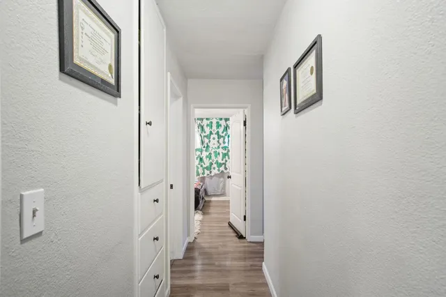 a view of a hallway with wooden floor and a bathroom
