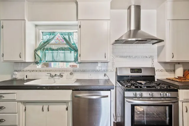 a kitchen with stainless steel appliances granite countertop a stove and a white cabinets