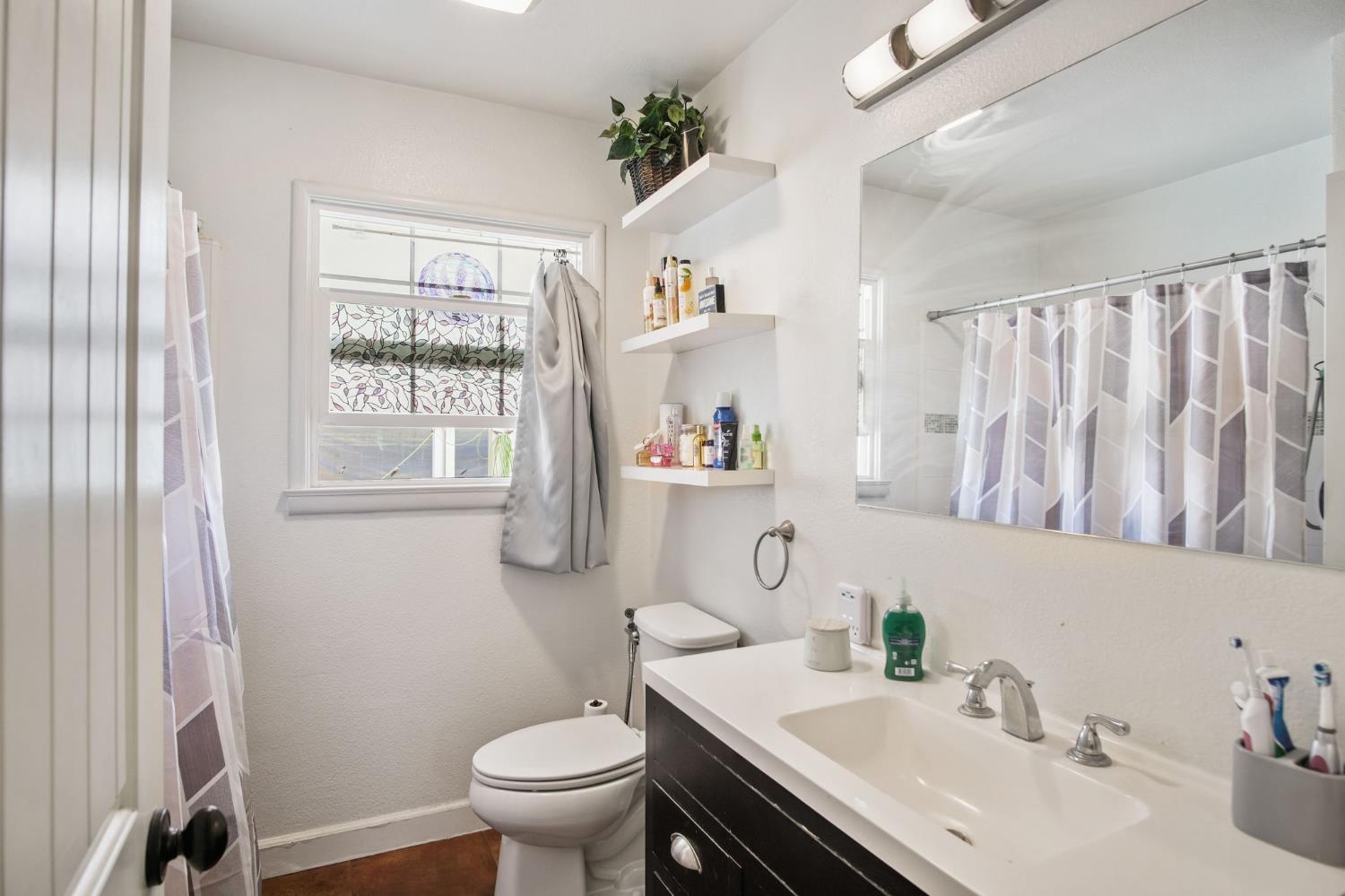 1725 Bronson Avenue Modesto, CA 95350 - Photo 10 of 17 a bathroom with a sink a toilet and a mirror