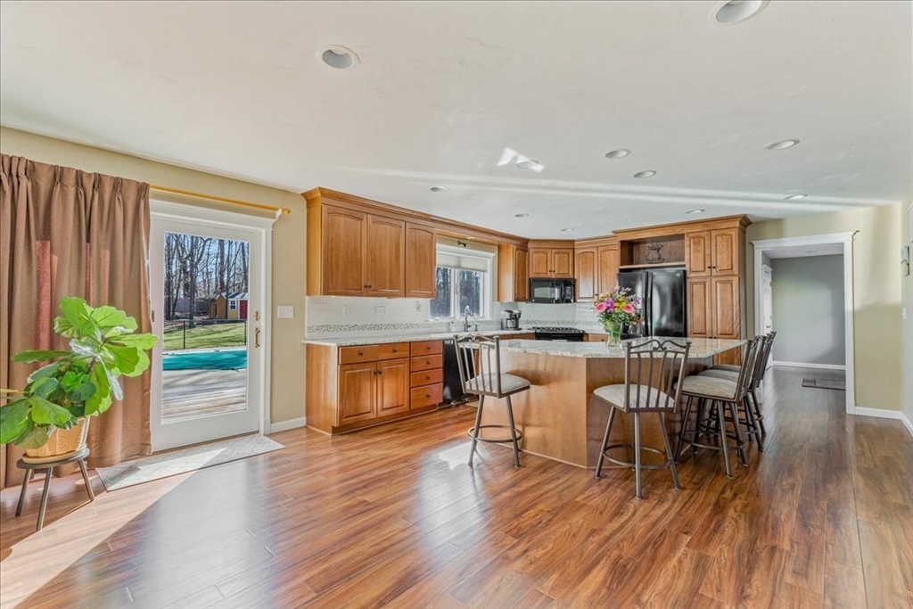 14 Robinson Road Rochester, MA 02770 - Photo 7 of 42 a kitchen with stainless steel appliances granite countertop a stove top oven a dining table and chairs with wooden floor