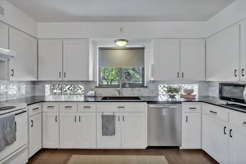 a kitchen with white cabinets white stainless steel appliances and sink