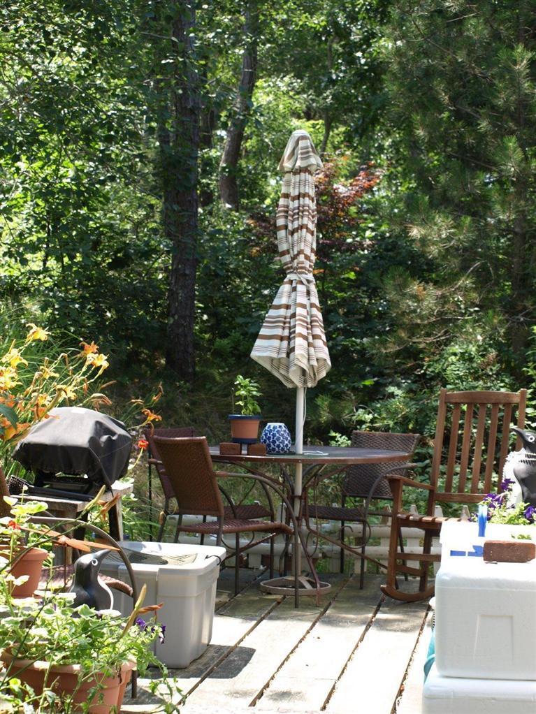 86 Shore Road, Unit 15 Truro, MA 02666 - Photo 11 of 23 a view of a patio with table and chairs potted plants with wooden fence